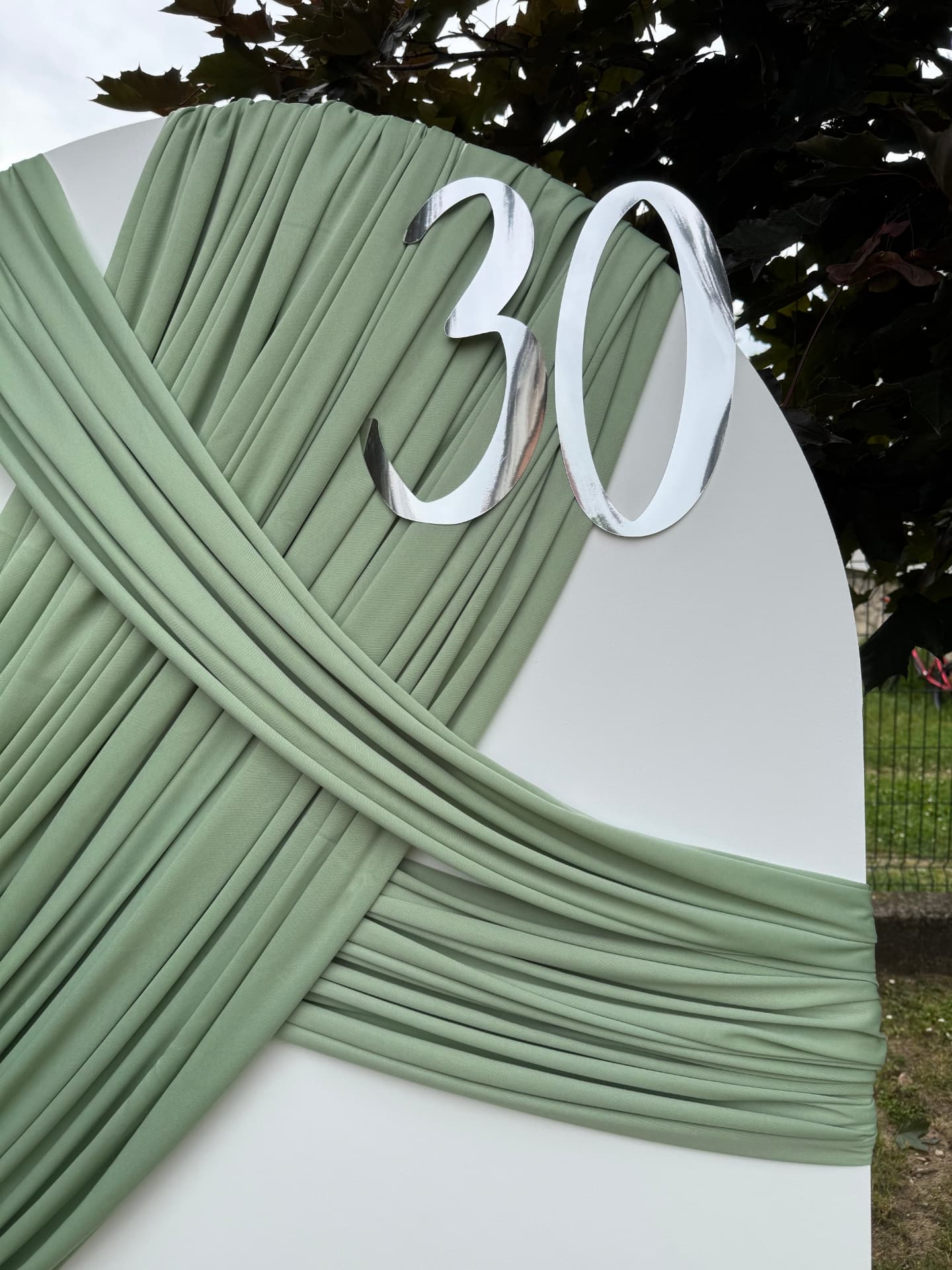 Detalj prepletene zelene draperije sa srebrnim brojem 30