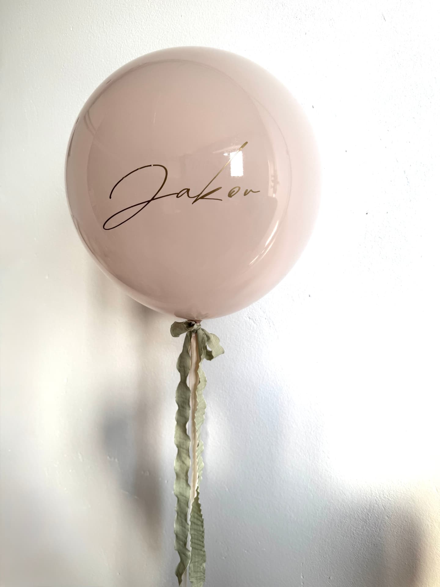 Veliki puder roza balon sa zlatnim imenom i zelenim vrpcama