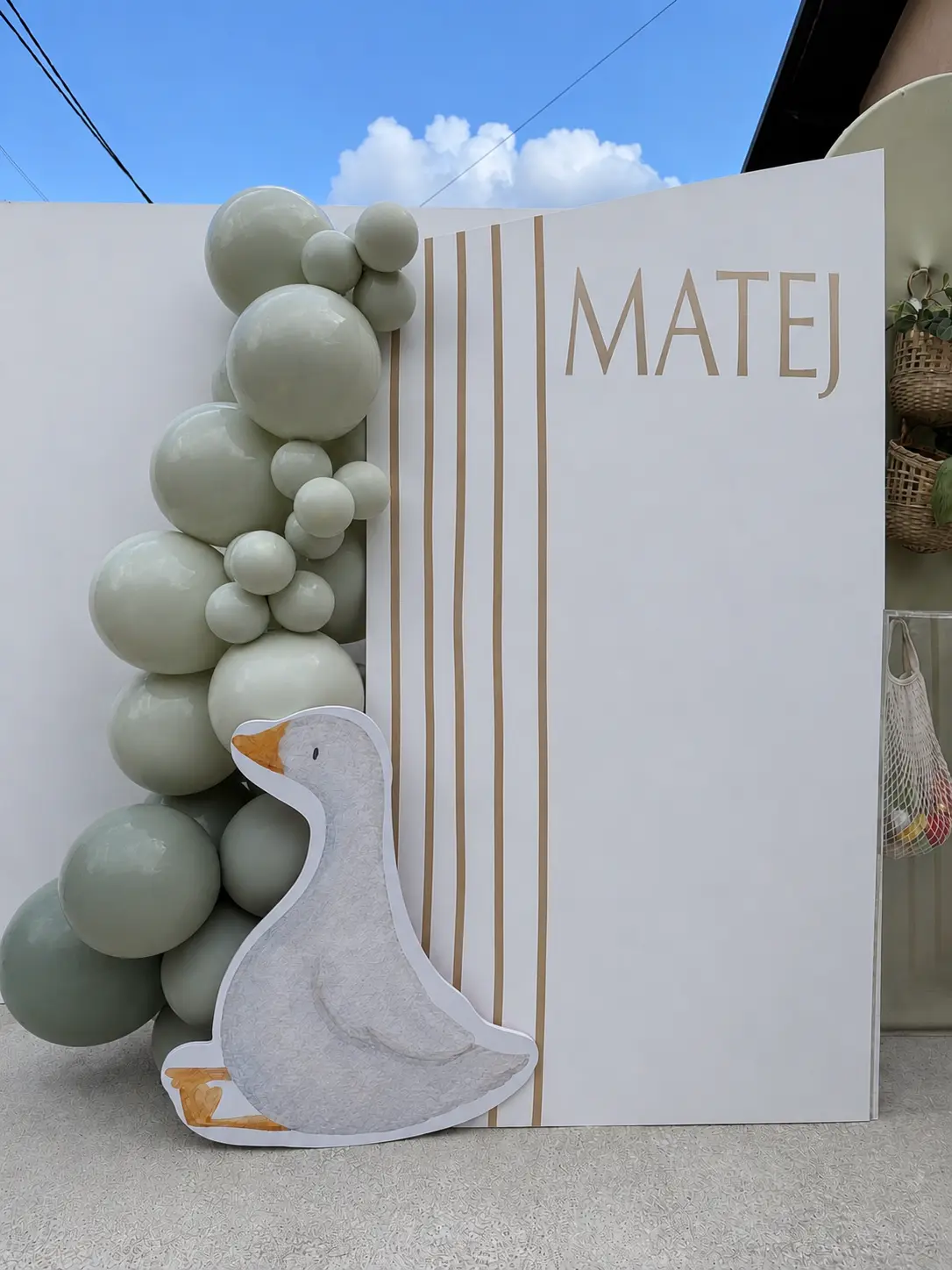 Bijela kulisa sa zlatnim natpisom MATEJ i zelenom balonskom girlandom